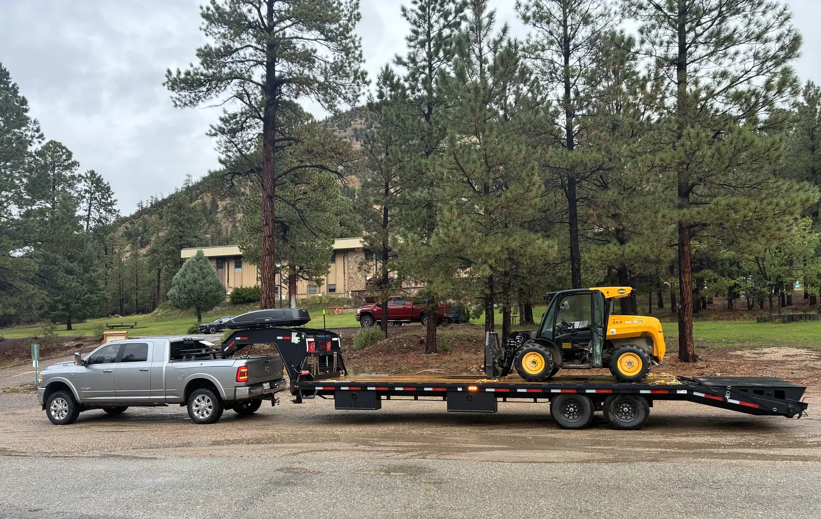 E3 Logistics truck hauling heavy equipment on a gooseneck trailer